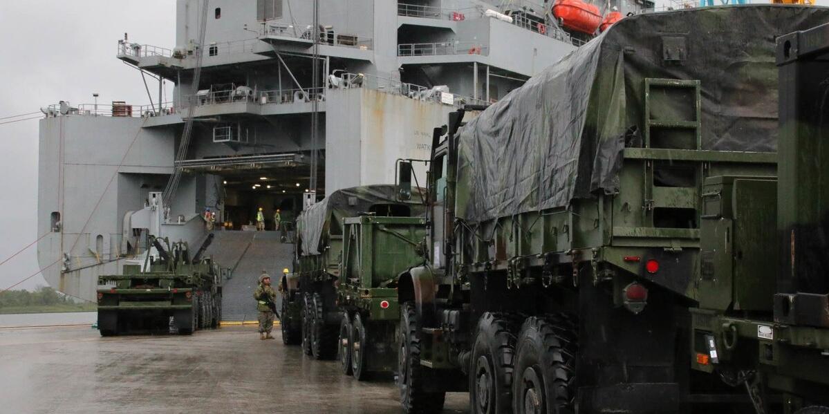 Military vehicles rolling on to a ship