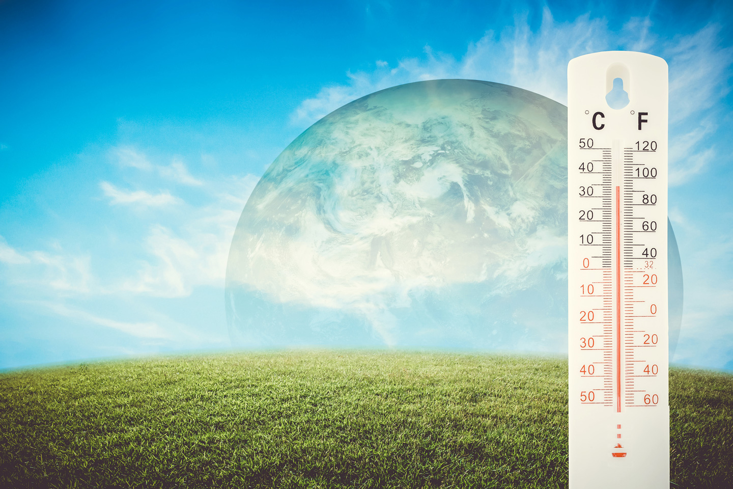 A green field and blue sky with clouds with a superimposed image of the earth in the background and a thermometer showing a high temperature in the foreground