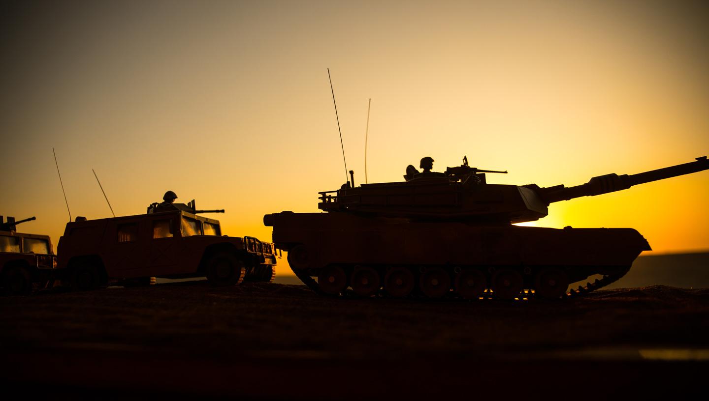 A line of army vehicles at sunset