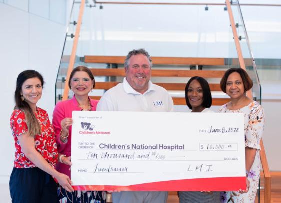 LMI's president and CEO, Doug Wagoner, presents a check for $10,000  a representative from Children'’s National Hospital. For over 30 years, LMI's annual Children's Hospital Benefit has been one of our most cherished traditions. 