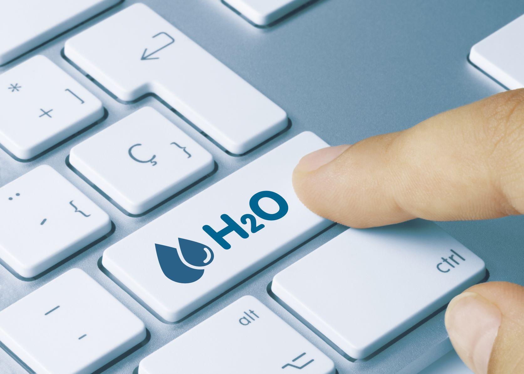 A finger over a keyboard, reaching for a key labeled H2O with a water symbol